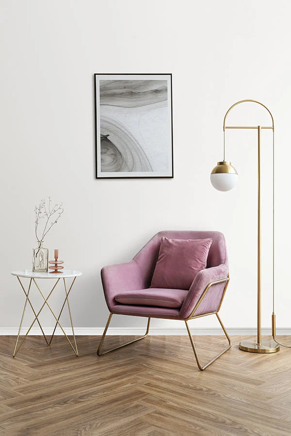 Framed abstract artwork displayed beside a pink velvet armchair